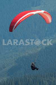 Paraglider flying over mountains on a summer day
