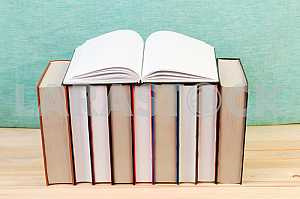 Open book, stack of hardback books on wooden table. Back to school. Copy space