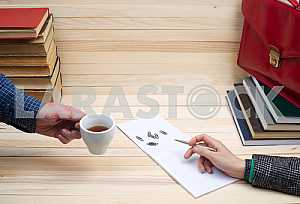 On a wooden table books, documents, calculator, red briefcase.