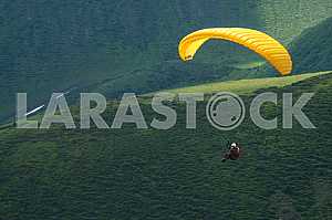 Paraglider flying over mountains on a summer day