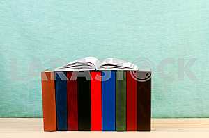 Open book, stack of hardback books on wooden table. Back to school. Copy space