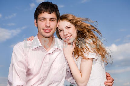 Portrait of a young happy couple against a backdrop of blue sky
