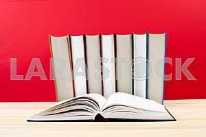 Открытая книга, стопка книг в твердом переплете на деревянном столе. Обратно в школу. Копирование пространства