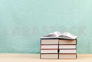 Открытая книга, стопка книг в твердом переплете на деревянном столе. Обратно в школу. Копирование пространства