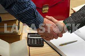 On a wooden table books, documents, calculator, red briefcase.