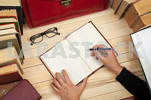 On a wooden table books, documents, calculator, red briefcase.