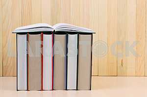 Открытая книга, стопка книг в твердом переплете на деревянном столе. Обратно в школу. Копирование пространства