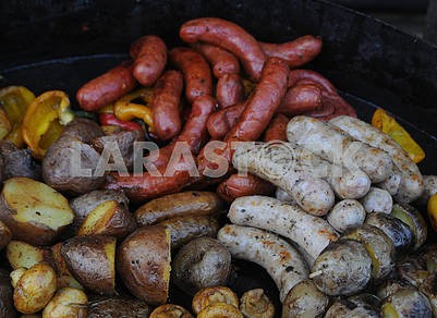 Печеный картофель и жареные колбасы на сковороде