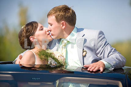 Bride and groom kissing on wedding auto
