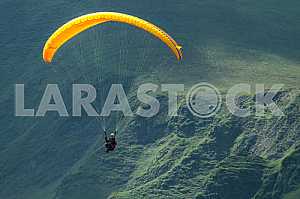 Paraglider flying over mountains on a summer day