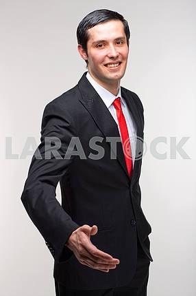 Молодой представитель человек в костюме держит руку , чтобы поприветствовать