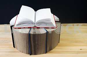 Открытая книга, стопка книг в твердом переплете на деревянном столе. Обратно в школу. Копирование пространства