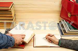 On a wooden table books, documents, calculator, red briefcase.