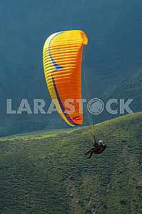 Paraglider flying over mountains on a summer day