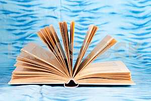 Old and used hardback books or text books on wooden table. Books and reading are essential for self improvement, gaining knowledge and success in our careers, business and personal lives. Copy space