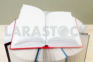 Открытая книга, стопка книг в твердом переплете на деревянном столе. Обратно в школу. Копирование пространства