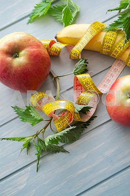 Fruits and vegetables, organic nettle, tape measure on blue wooden background. Concept of proper nutrition.