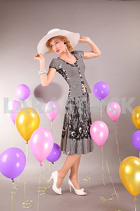 beautiful young girl in light dress a hat on background balloons
