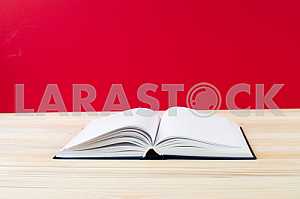 Открытая книга, стопка книг в твердом переплете на деревянном столе. Обратно в школу. Копирование пространства