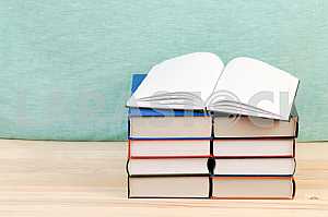 Открытая книга, стопка книг в твердом переплете на деревянном столе. Обратно в школу. Копирование пространства