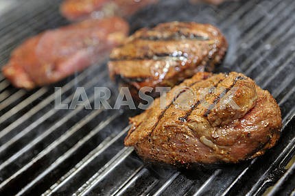 Beef steak cooking on an open flame grill