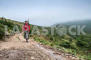 A man with a backpack riding a bike on a mountain road in the Carpathians
