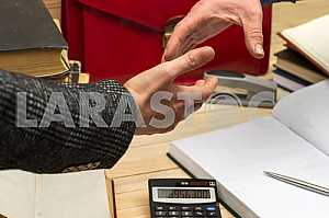On a wooden table books, documents, calculator, red briefcase.