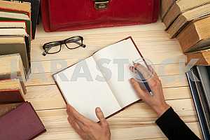 On a wooden table books, documents, calculator, red briefcase.