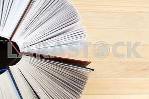 Открытая книга, стопка книг в твердом переплете на деревянном столе. Обратно в школу. Копирование пространства