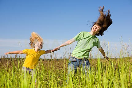 Happy woman and girl making exercises on field.
