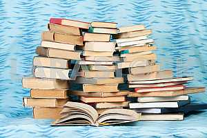 Old and used hardback books or text books on wooden table. Books and reading are essential for self improvement, gaining knowledge and success in our careers, business and personal lives. Copy space