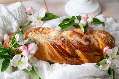 Traditional wicker sweet bread with strawberries. Sweet wheat bun on a wooden background and spring flowers. Rustic style.
