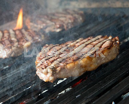 стейк из говядины приготовления пищи на открытом гриле пламени