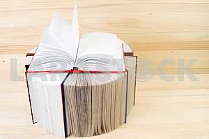 Open book, stack of hardback books on wooden table. Back to school. Copy space