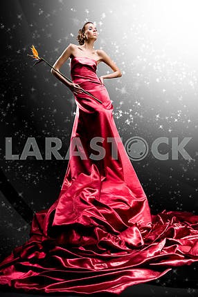 Beautiful girl in long red dress holds exotic flower in hand