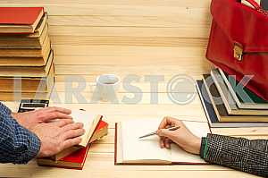 On a wooden table books, documents, calculator, red briefcase.