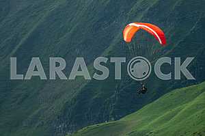 Paraglider flying over mountains on a summer day