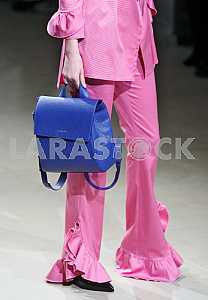 Model in a pink dress holding a blue bag during a demonstration dress by Ukrainian designer Maryana Steshenko