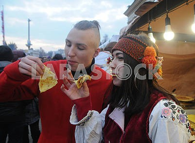 Мужчина и женщина в национальных костюмах едят блины