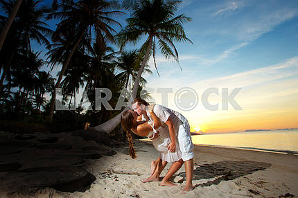 молодая пара, обниматься на пляже на закате