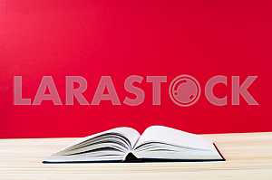 Открытая книга, стопка книг в твердом переплете на деревянном столе. Обратно в школу. Копирование пространства