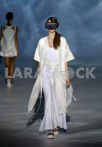 Model c mobile phone attached to the face demonstrates outfit by Ukrainian designer Olena Dats