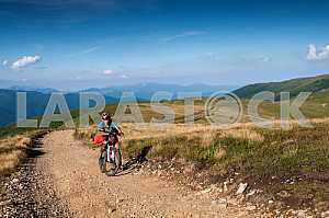 A man with a backpack riding a bike on a mountain road in the Carpathians