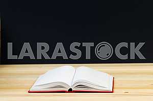 Открытая книга, стопка книг в твердом переплете на деревянном столе. Обратно в школу. Копирование пространства