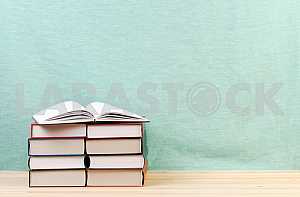 Открытая книга, стопка книг в твердом переплете на деревянном столе. Обратно в школу. Копирование пространства
