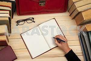 On a wooden table books, documents, calculator, red briefcase.