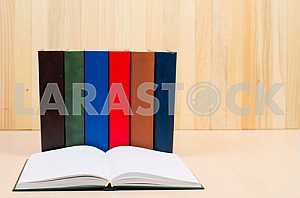 Открытая книга, стопка книг в твердом переплете на деревянном столе. Обратно в школу. Копирование пространства
