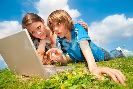 Два улыбается подростков с ноутбуком отдыхает на лугу .