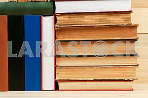 Открытая книга, стопка книг в твердом переплете на деревянном столе. Обратно в школу. Копирование пространства