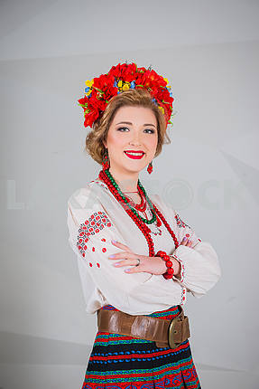 a beautiful girl in National Ukrainian Costume. captured in studio. Embroidery and jacket. wreath. circlet of flowers. red lips